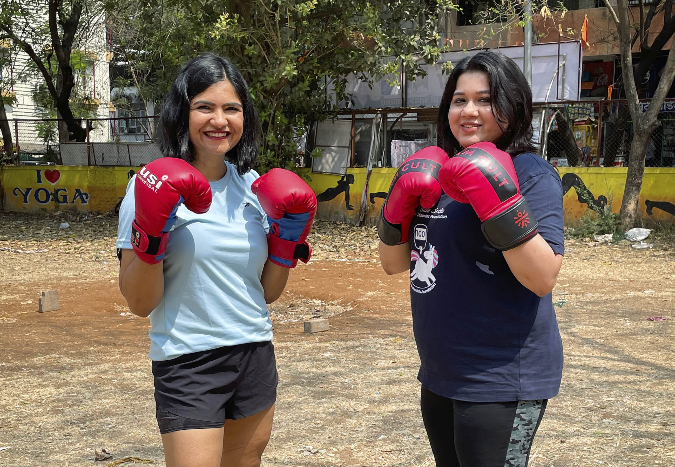Two women from India wearing boxing gloves and smiling