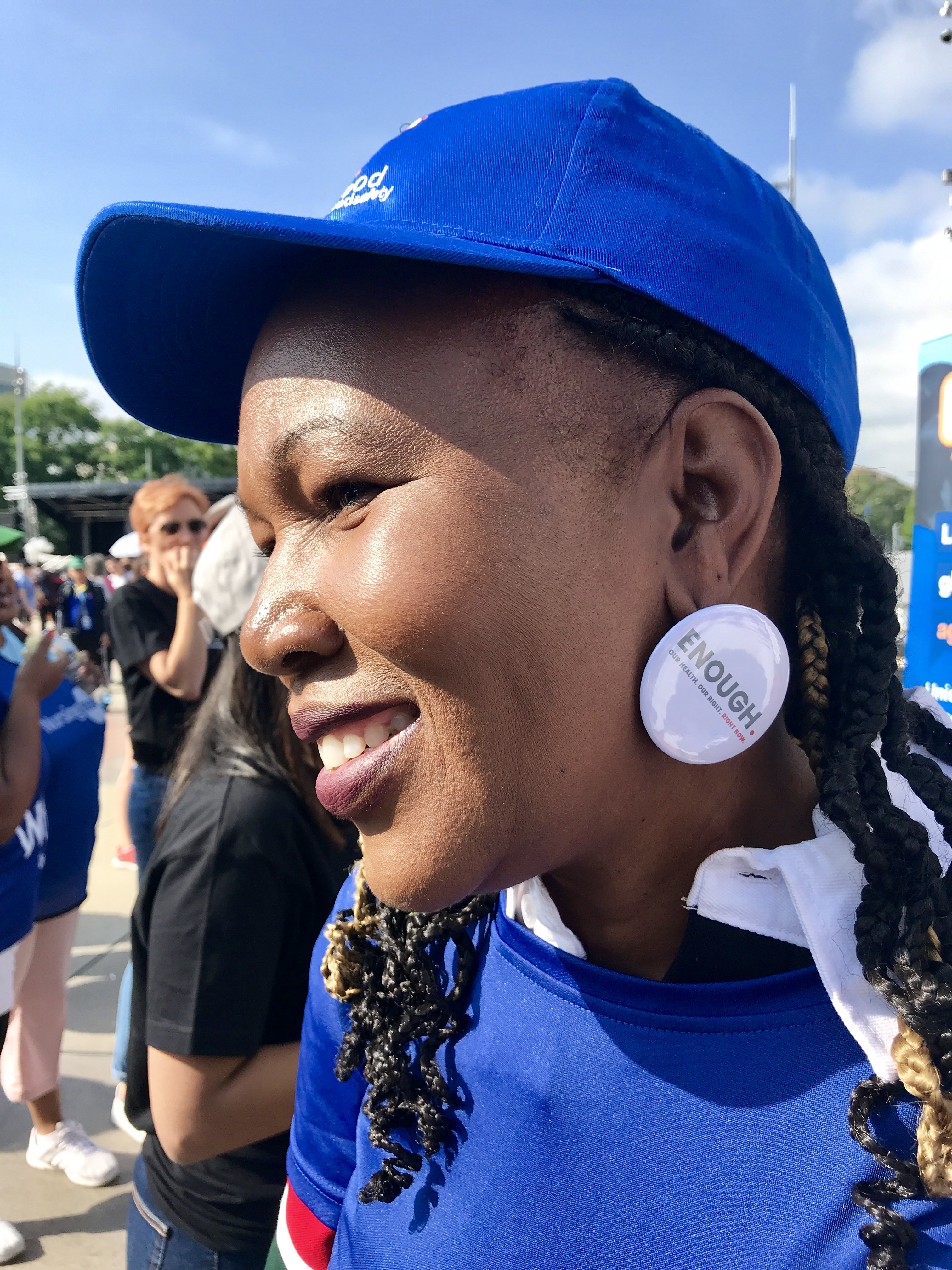 A woman wears a button of the Enough campaign as an earring.