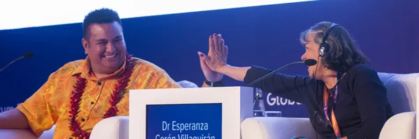 Two people on a panel at the Global NCD Alliance Forum high-fiving