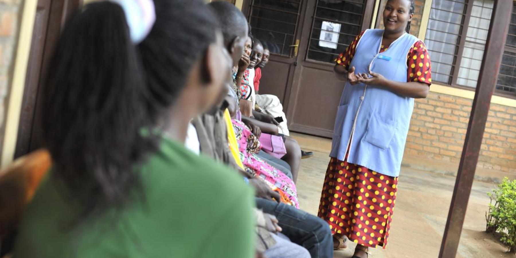 A health worker speaks to clients waiting for services at a clinic in Rwanda