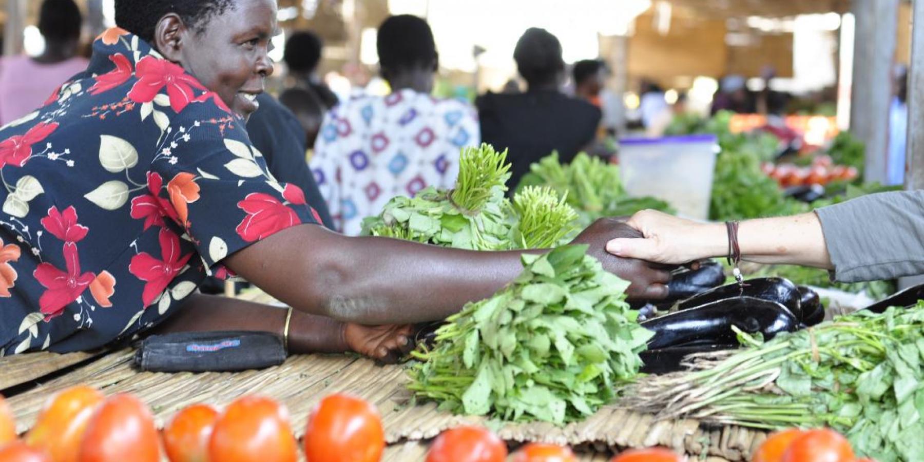 A member of a women's microfinance group sells fruits and vegetables in Gulu, Uganda. 
