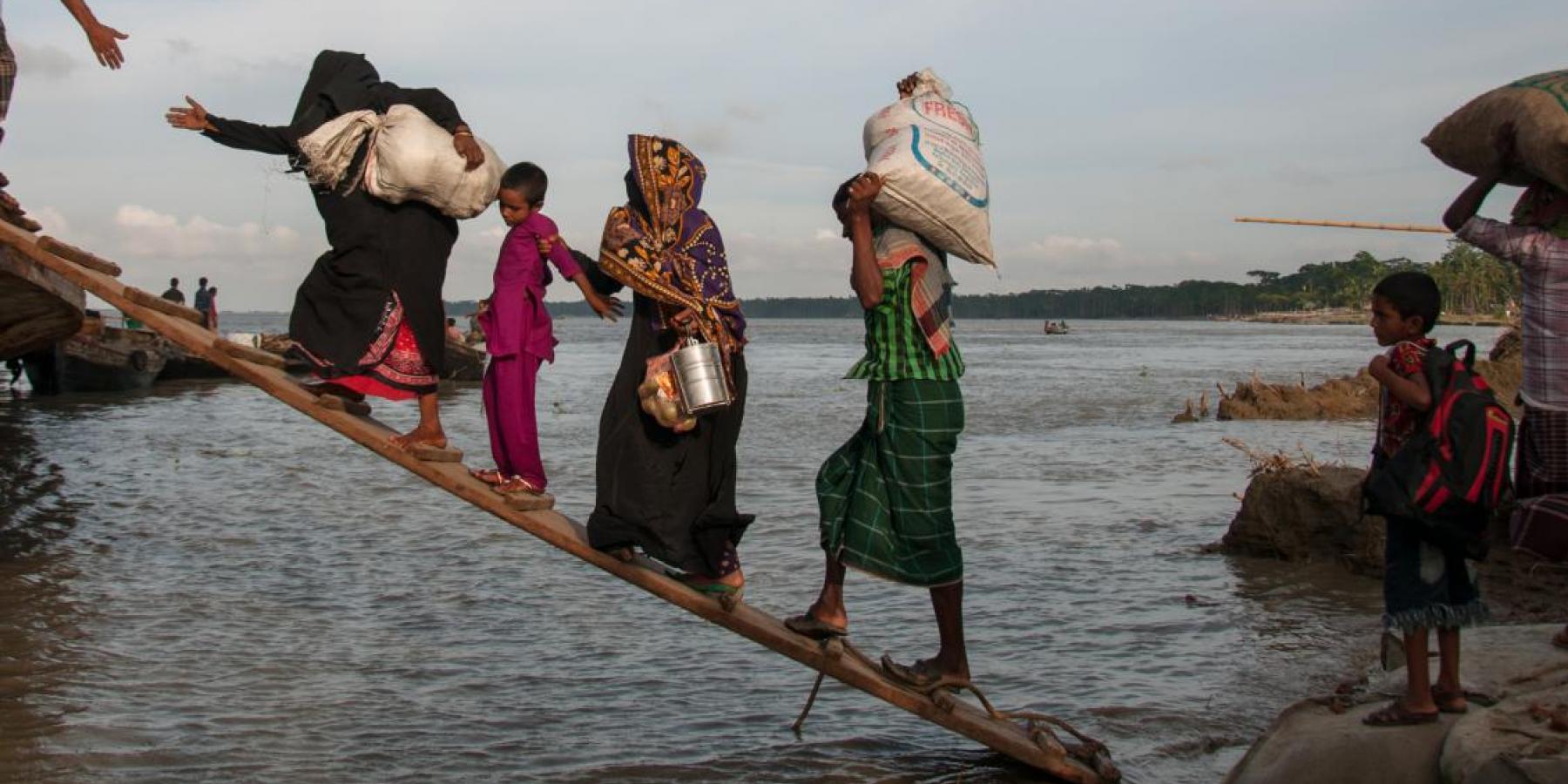 Climate-affected internally displaced persons board a boat to travel to Dhaka, Bangladesh. 