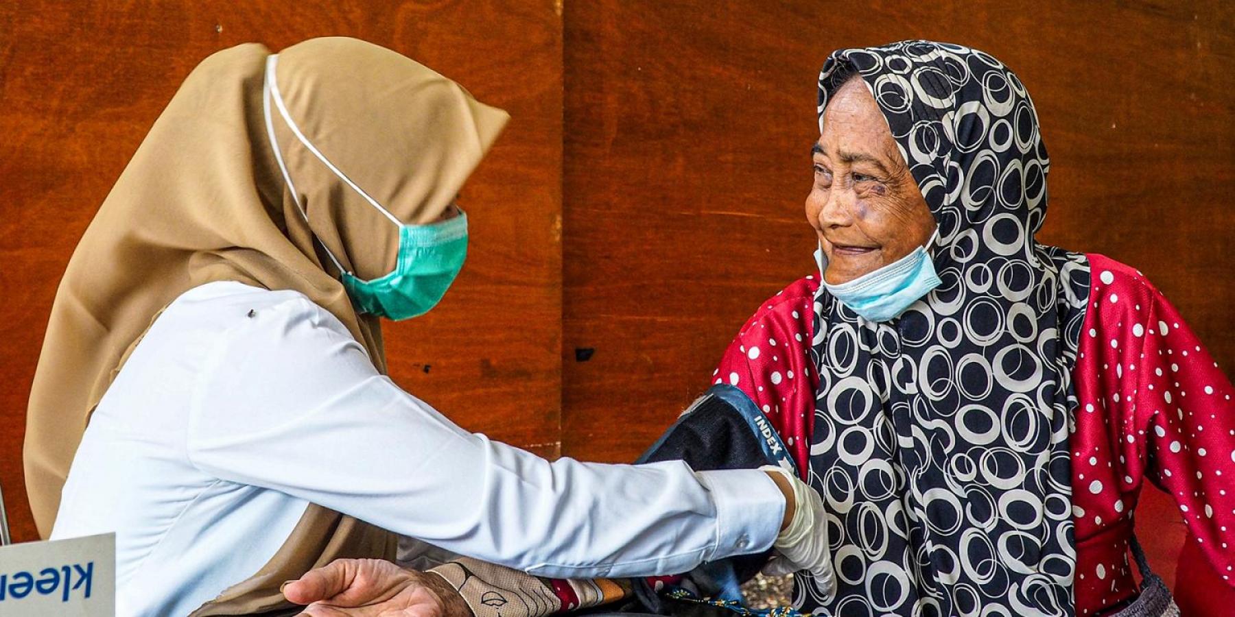health worker in indonesia taking blood pressure