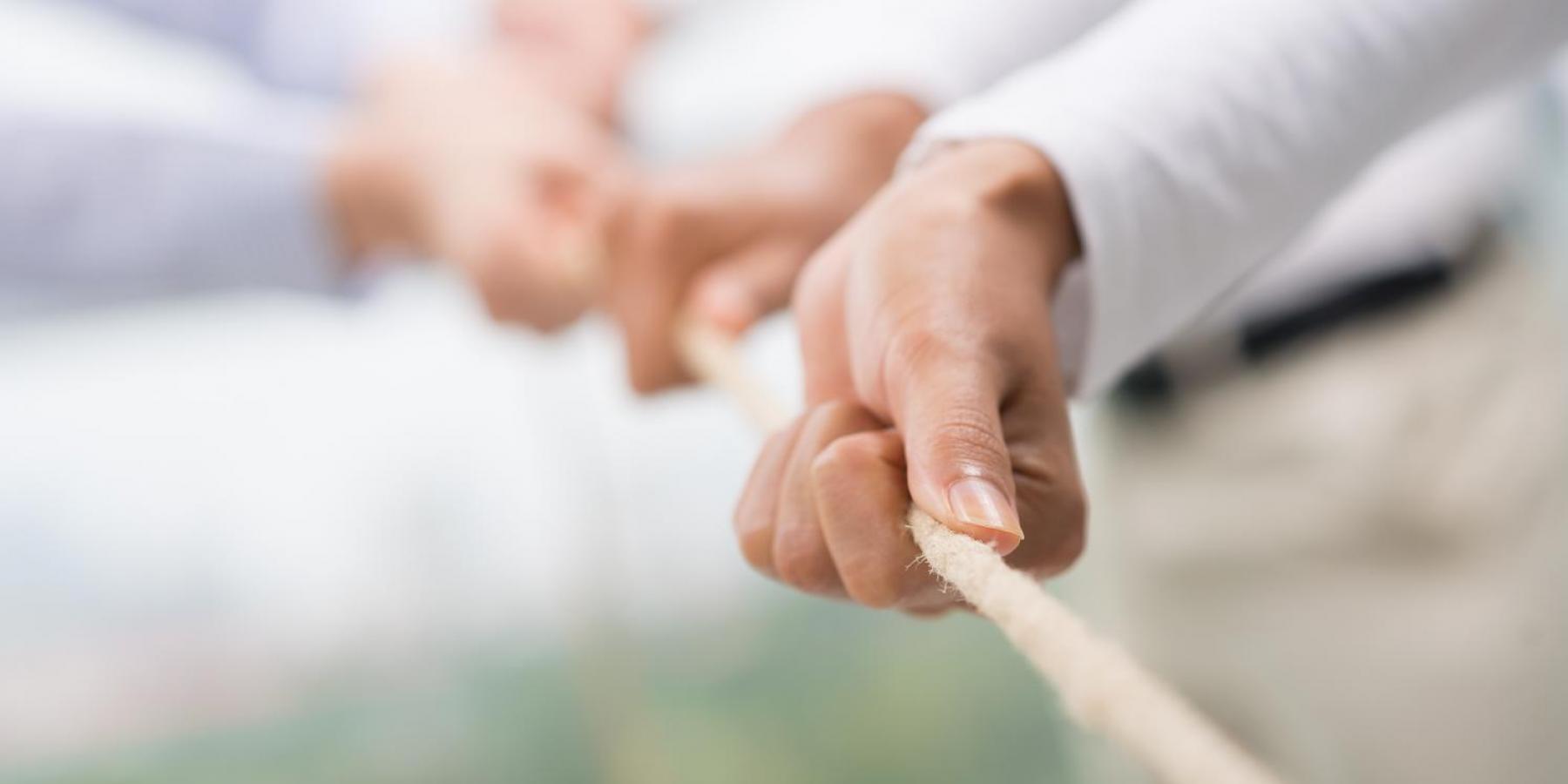 Close up of hands pulling a rope