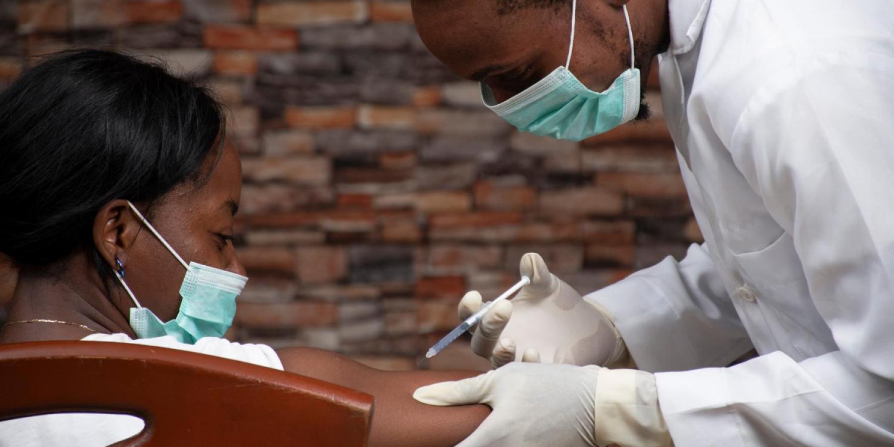 A doctor providing a covid shot in an African setting 