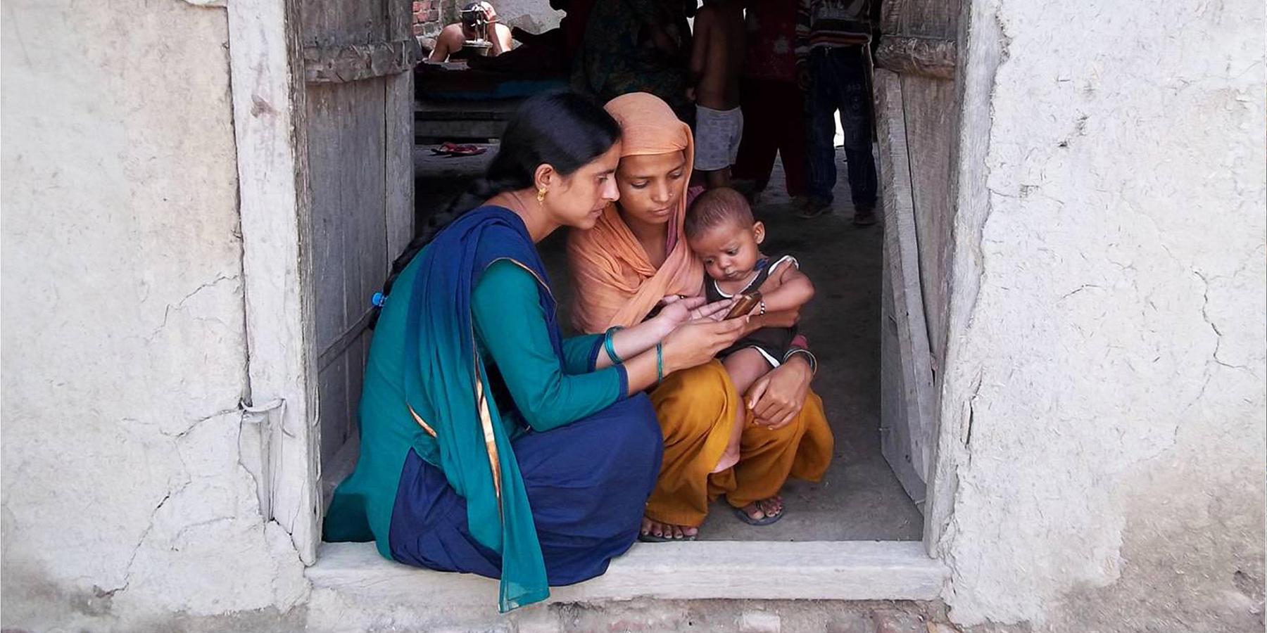 A community health worker uses mHealth to counsel a new mother in Badagaon, India