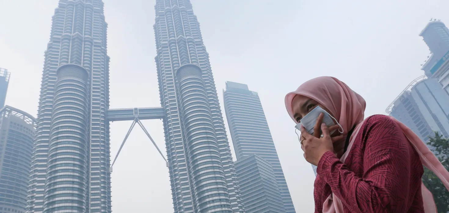 woman wearing mask covers her mouth to protect herself from air pollution in Kuala Lumpur