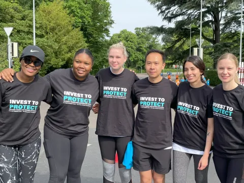 Six Global Week for Action on NCDs advocates smiling with t-shirts that say 'Invest to Protect' on them at the WHO Walk the Talk Event in Geneva.
