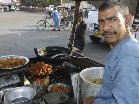 Man selling fried food in a street stall in India 