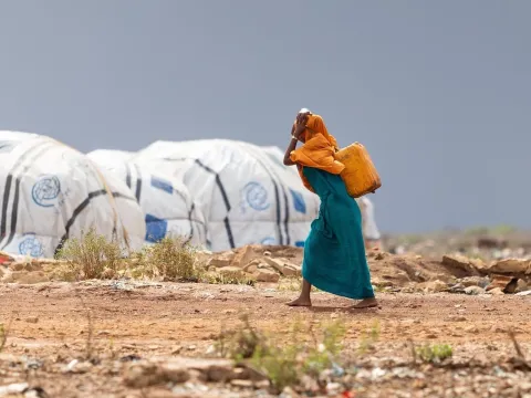 Woman carrying a drum in a humanitarian setting 