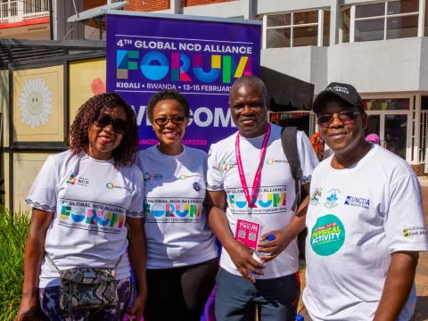 people smiling at kigali car free day in front of ncd alliance forum sign