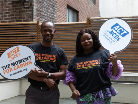 Two people african decent holding up 'act on ncds' signs