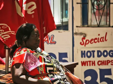 Portrait of a middle aged african fat woman waiting outdoor at fast food and hot dog kiosk
