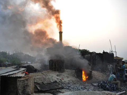 Road construction workers in Bangladesh surrounded by smoke 