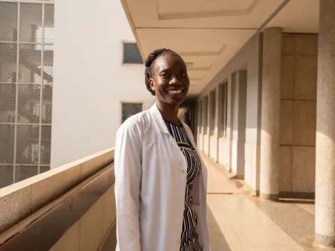 Woman doctor in Kenya smiling at the camera in outside hallway of hospital