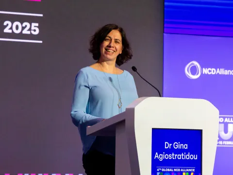 lady on a podium smiling during the global ncd alliance forum in kigali