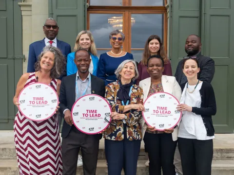 ncd advocates at a meeting in geneva smiling and holding time to lead campaign signs