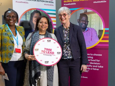 NCD advocates smiling at an event with a time to lead sign for NCD global week for action