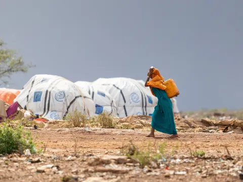 Somali woman carrying drum in a refugee camp in Africa
