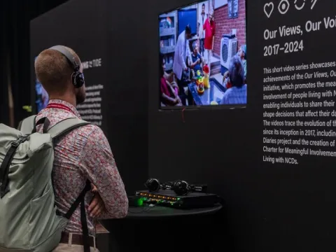 A delegate checks out the interactive exhibition of the Our Views, Our Voices initiative in the Community Zone at the Global NCDA Forum 2025