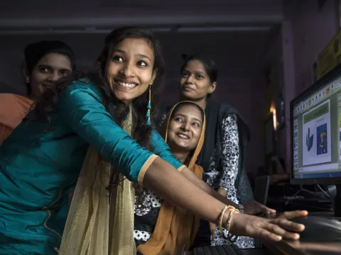 Girls in India smiling at computer with e-learning platform 