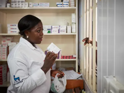 Pharmacist preparing prescription and giving indications to patient.