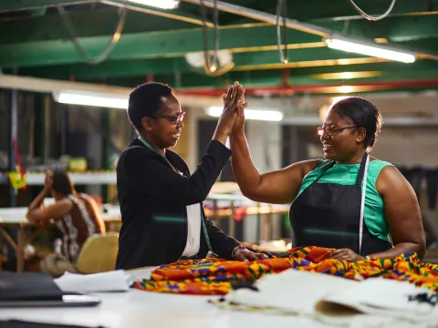 Two african women in textile factory doing a high five