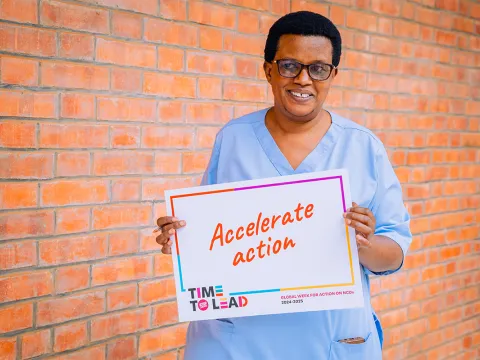 A nurse in Rwanda holding "Accelerate Action" card