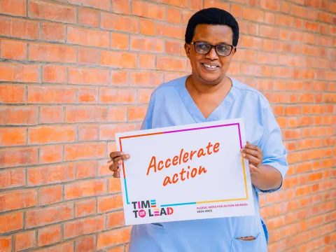 A nurse in Rwanda holding "Accelerate Action" card