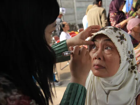 A health worker is examining the eyes of a patient at a health social service event in Surabaya Indonesia