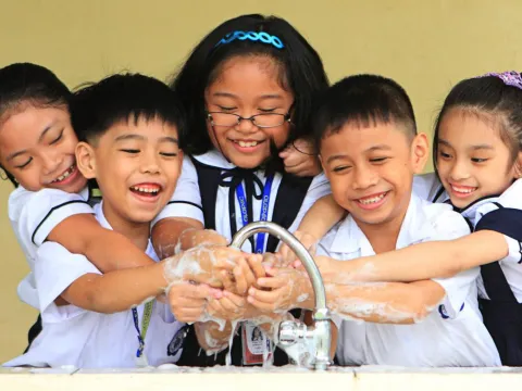 School children in the Philippines wash their hands together at a sink. 