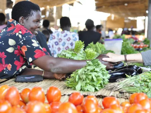 A member of a women's microfinance group sells fruits and vegetables in Gulu, Uganda. 