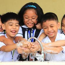 School children in the Philippines wash their hands together at a sink. 