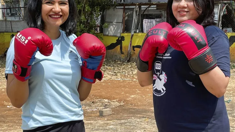 Two women from India wearing boxing gloves and smiling