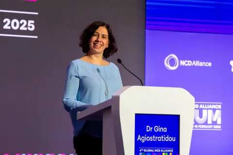 lady on a podium smiling during the global ncd alliance forum in kigali