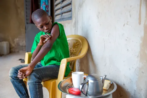 Boy administering an insulin shot on his left arm