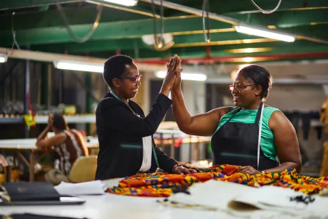 Two african women in textile factory doing a high five