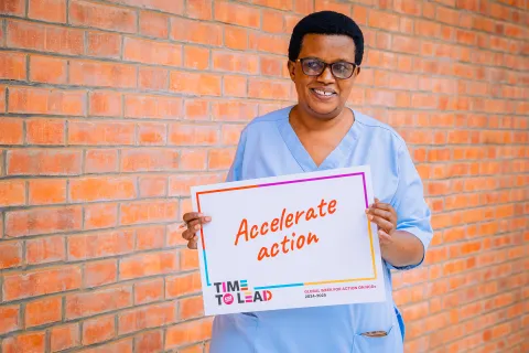 A nurse in Rwanda holding "Accelerate Action" card