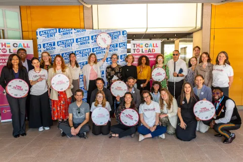 NCD Advocates gather for a picture holding "Time to Lead" banners