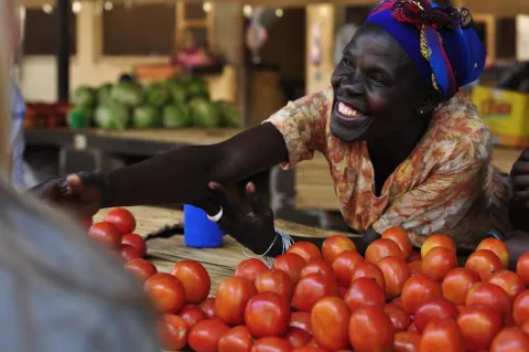 A member of a women's microfinance group sells produce at a market in Gulu, Uganda. 
