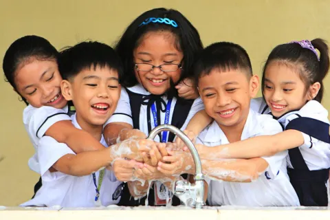 School children in the Philippines wash their hands together at a sink. 
