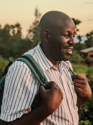 man smiling with backpack on walking in a field