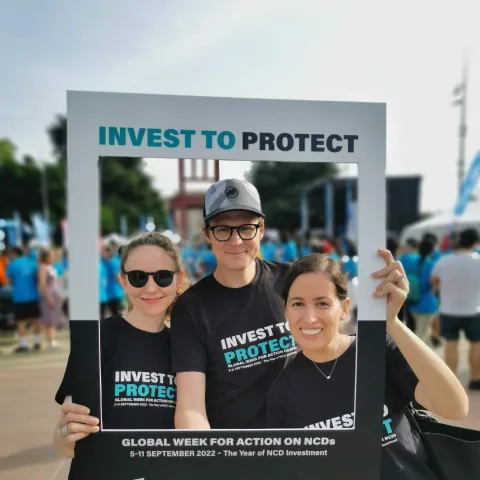 People holding up Invest to Protect on NCDs placard at a fun run in Geneva