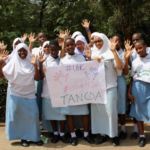 Tanzanian children holding up universal health coverage sign