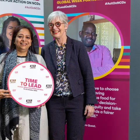 NCD advocates smiling at an event with a time to lead sign for NCD global week for action