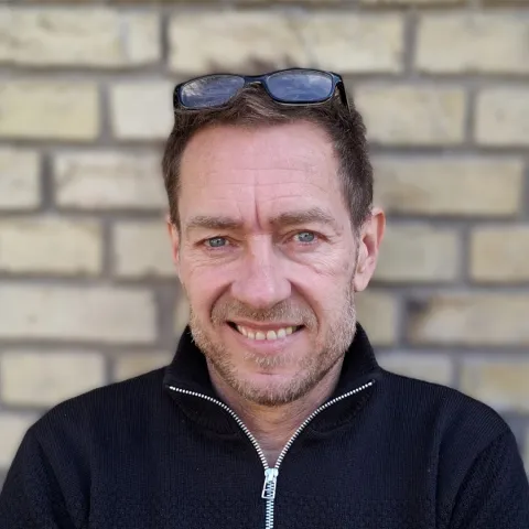 man smiling for portrait in front of brick wall