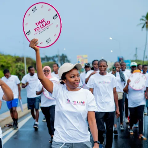 Tanzania NCDA advocate holding a "Time to Lead" clock during a Global Week for Action event in Dar es Salaam, Tanzania.