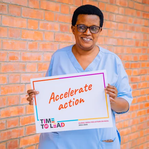 A nurse in Rwanda holding "Accelerate Action" card