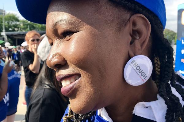 A woman wears a button of the Enough campaign as an earring.